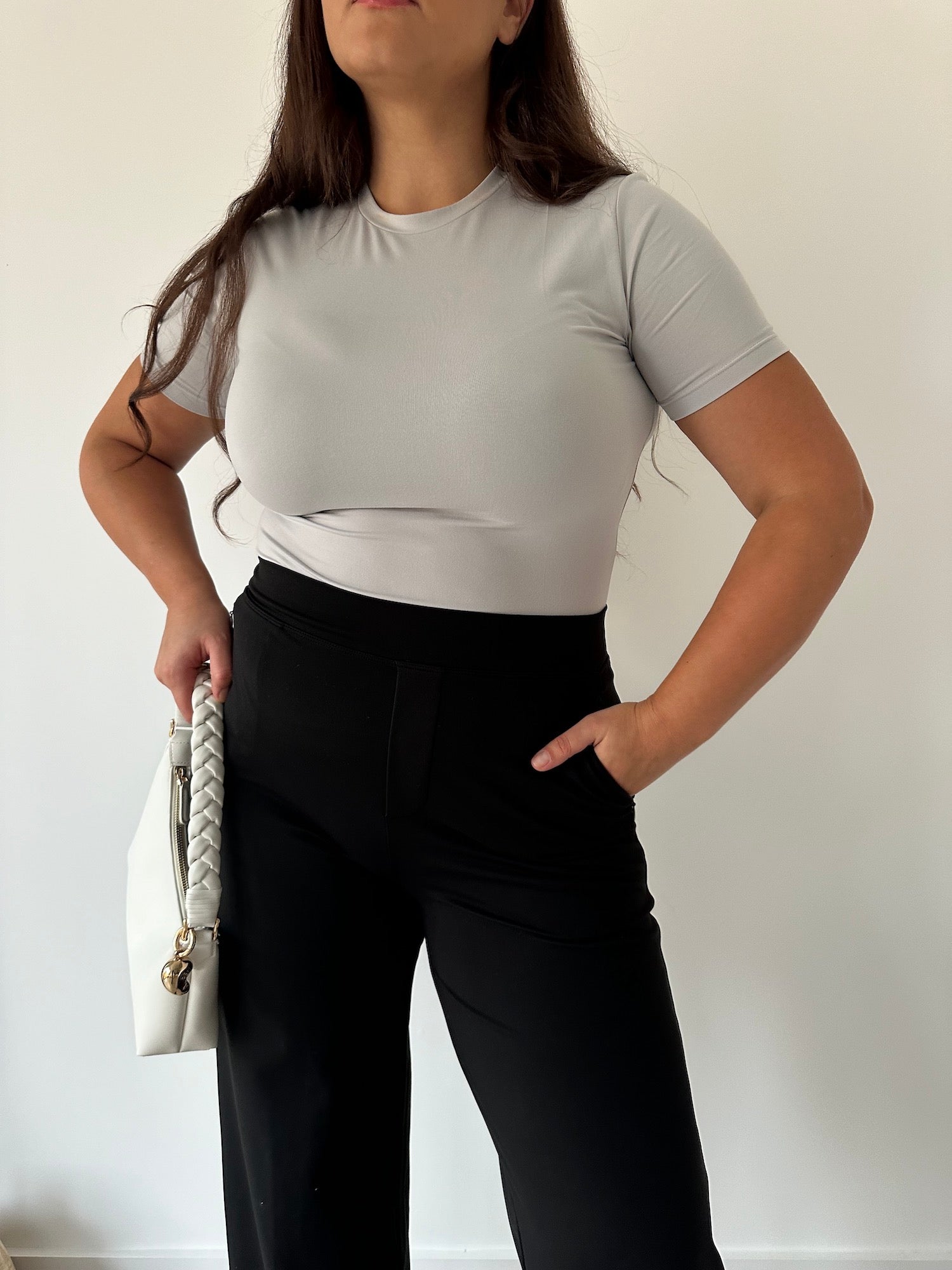 Woman in black Ninepine Asana Relaxed Pants and cloud grey soft top, showcasing comfortable stretch trousers styled for a minimal, everyday look